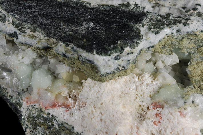 Detail of alpine vein with green prehnite, olive green clinozoisite, pink laumontite and white calcite from Markovice quarry in Czech Republic