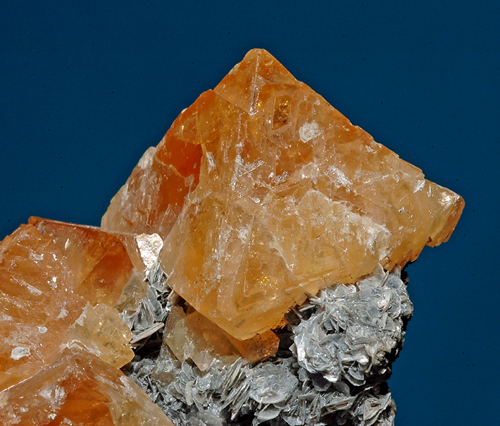 Tetragonal dipyramide shaped crystals of orange scheelite on muscovite mica from Yaogangxian Mine, Hunan Province, China